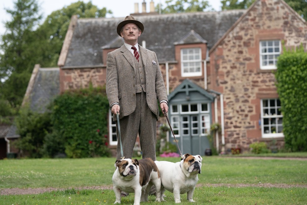 Major Horton standing outside with his two English bull dogs from Murder is Easy