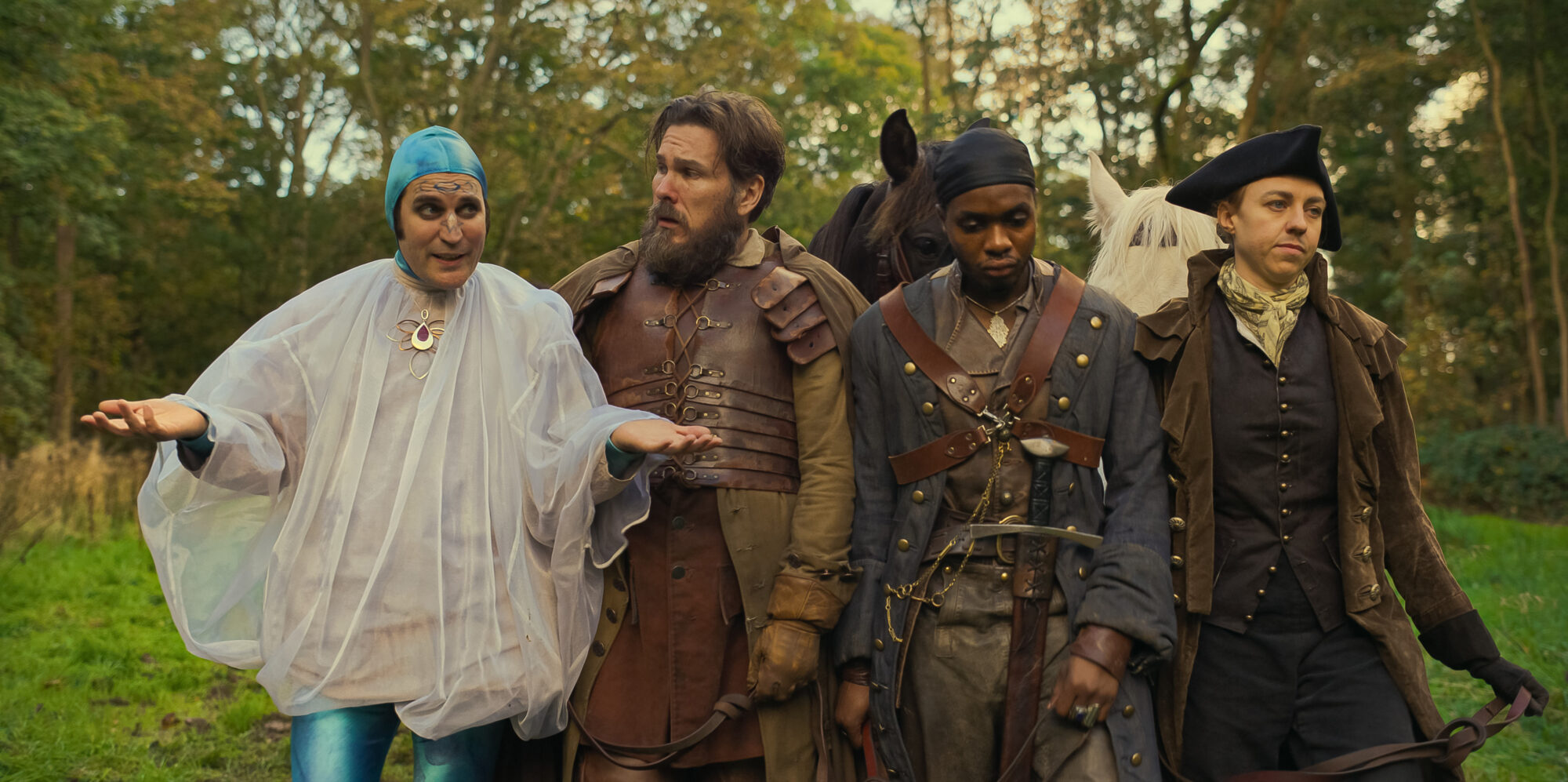 Dick Turpin is dressed up as a man from the future, with a blue cap and a poncho, walking with his new gang mates who are dressed up in more period appropriate clothing from The Completely Made-Up Adventures of Dick Turpin